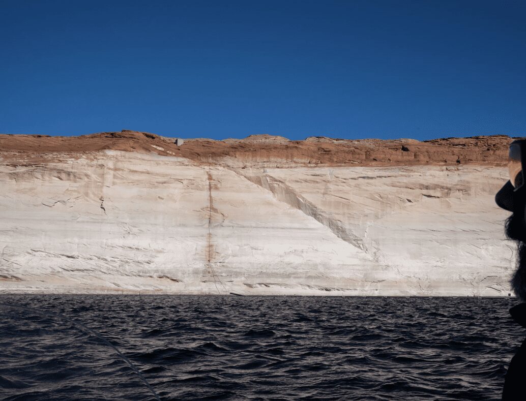 Boatside view of pale sandstone cliffs above water