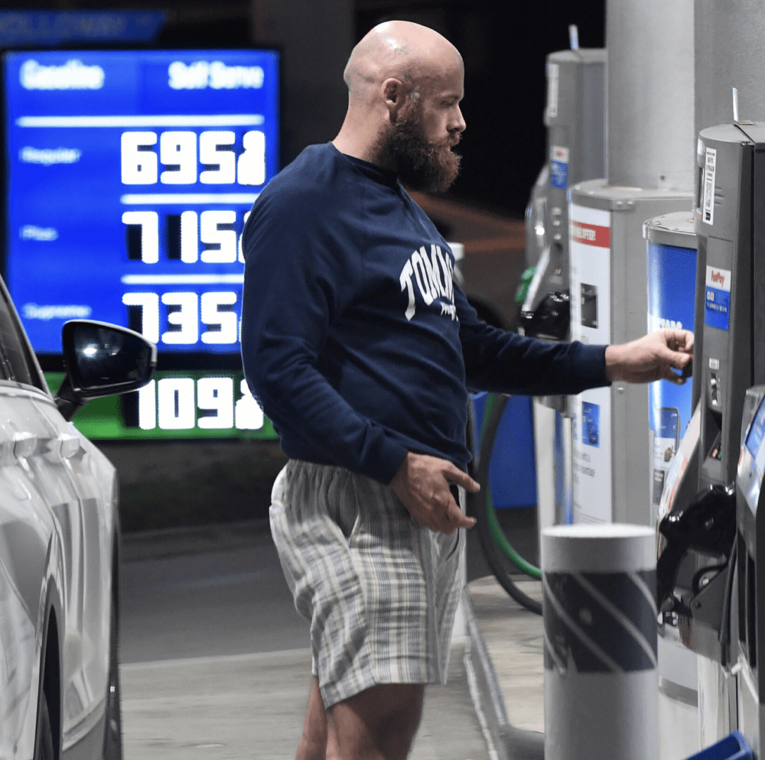 A man with beard in shorts at a gas station