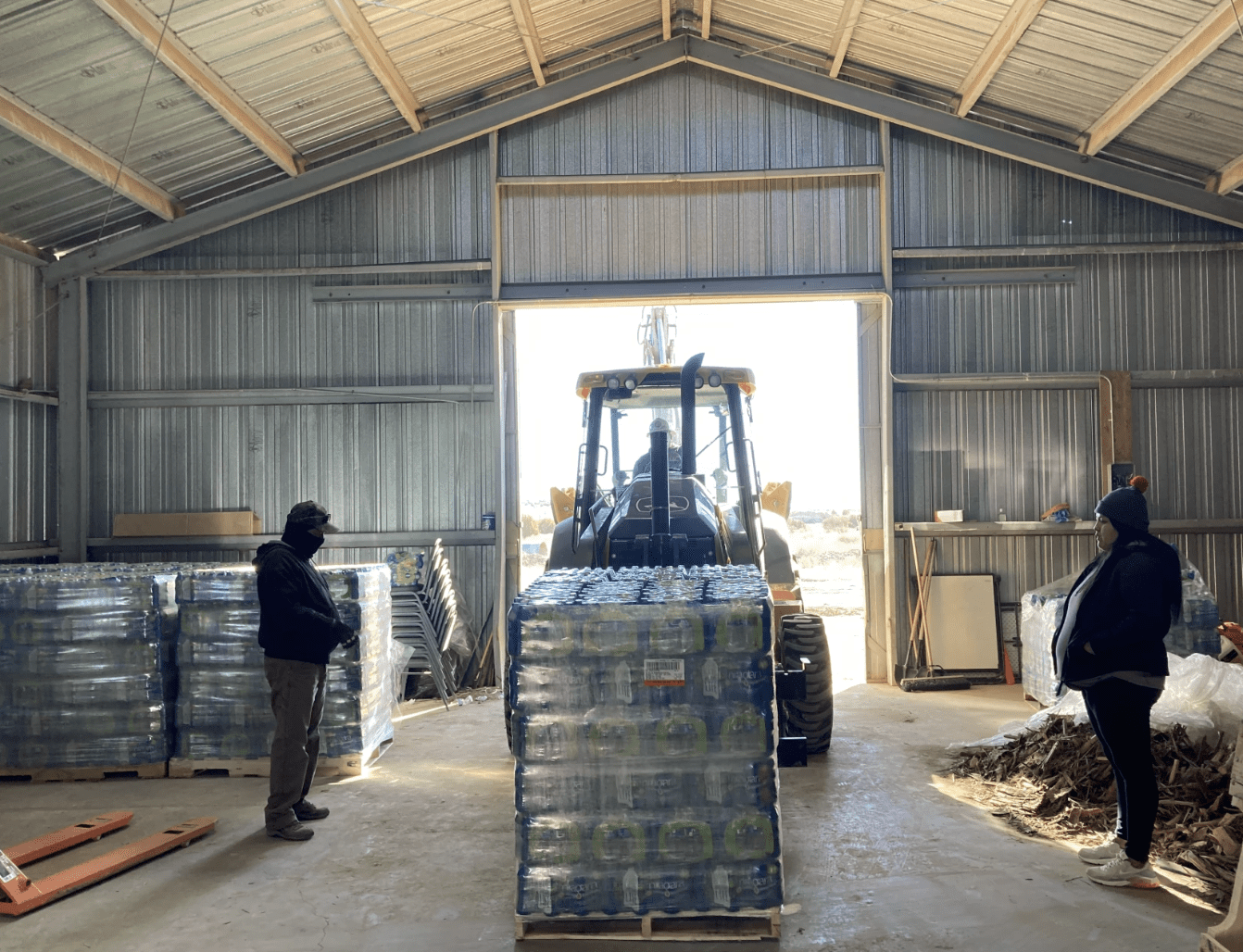 Tractor unloading pallets of bottled water