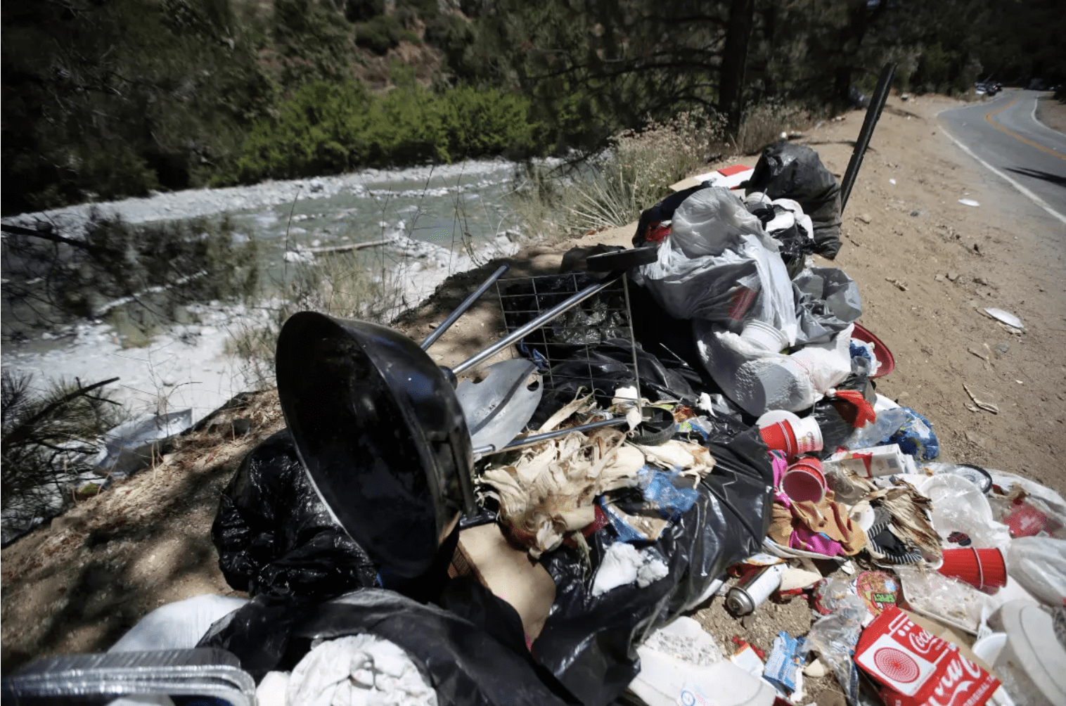 Roadside trash pile by mountain river