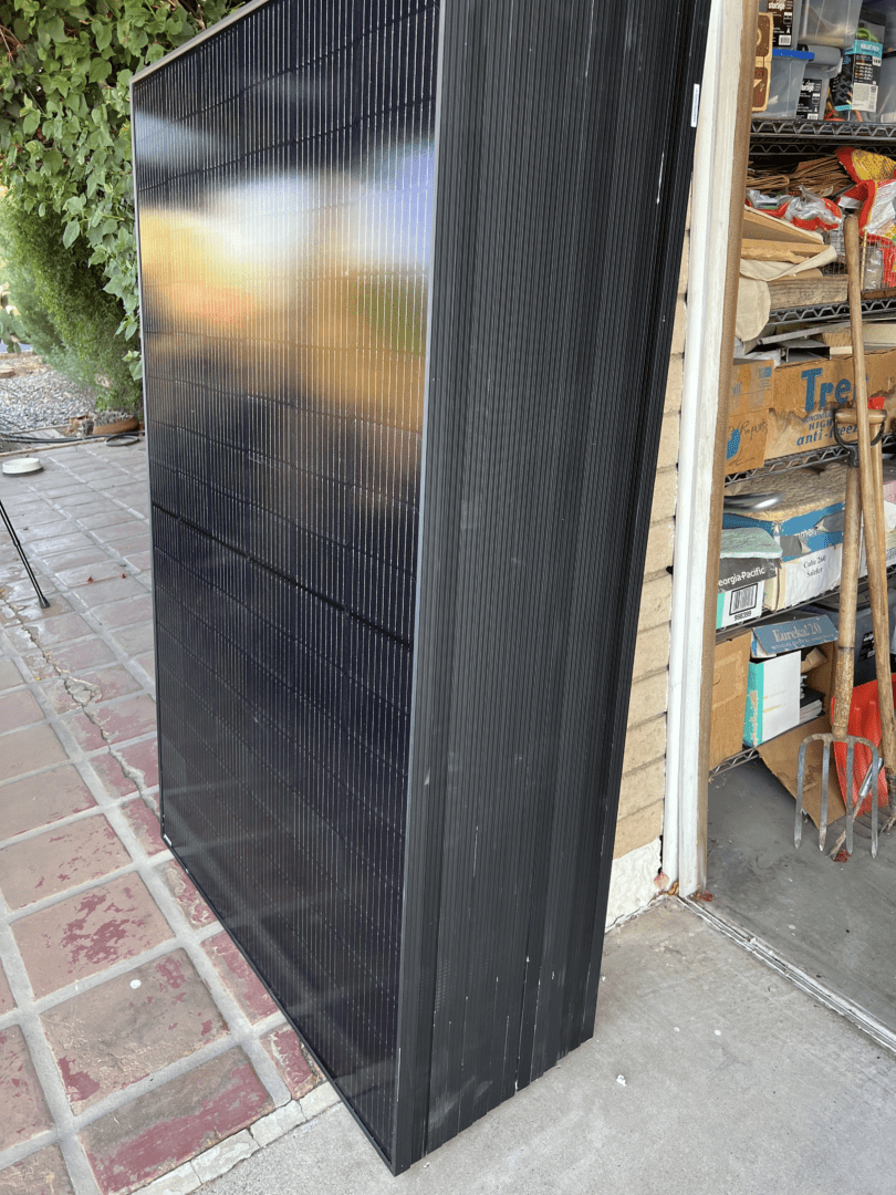 Stack of solar panels leaning by garage