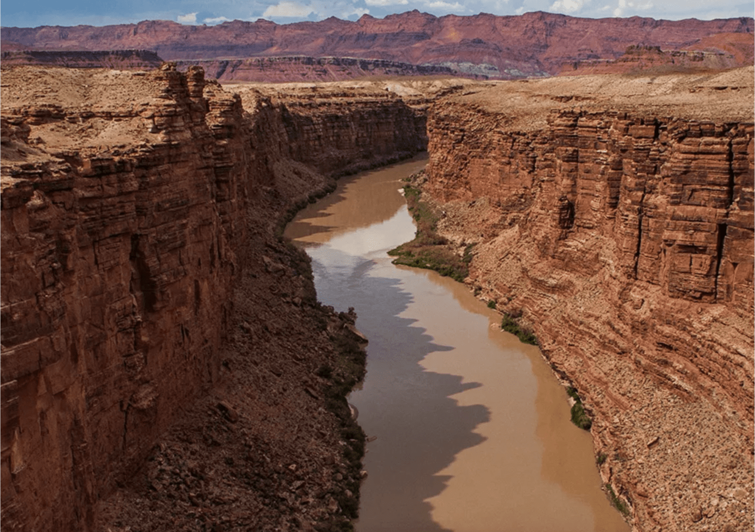 Muddy river winding through red rock canyon