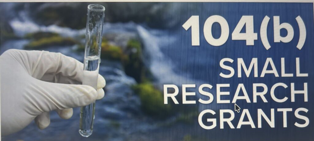 Gloved hand holding water sample near grant text
