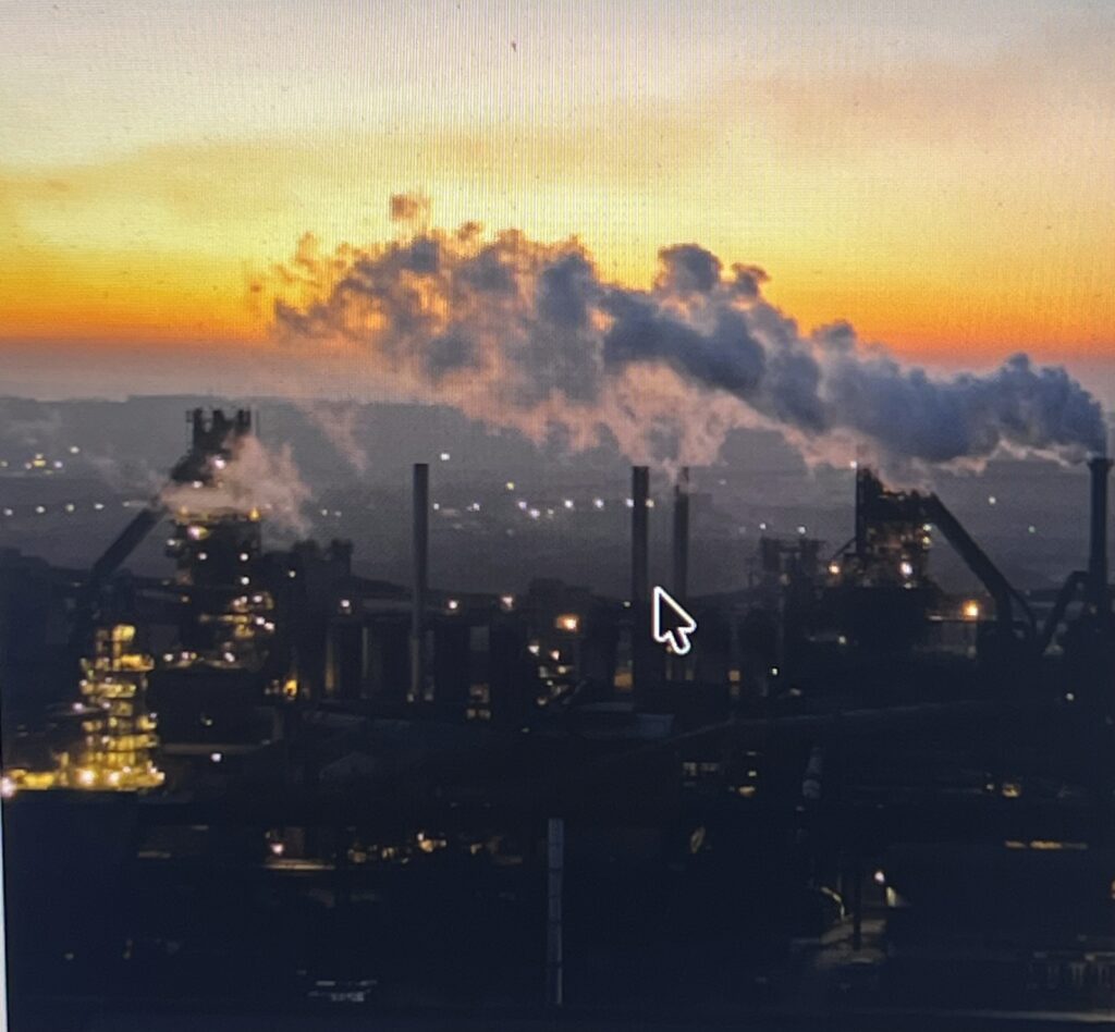 Industrial plant smokestacks emitting smoke at sunset